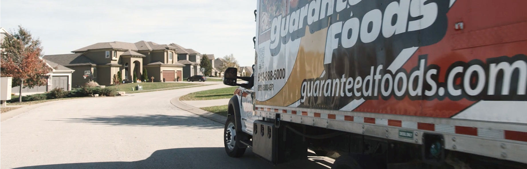 Guaranteed Foods delivery truck driving in a neighborhood